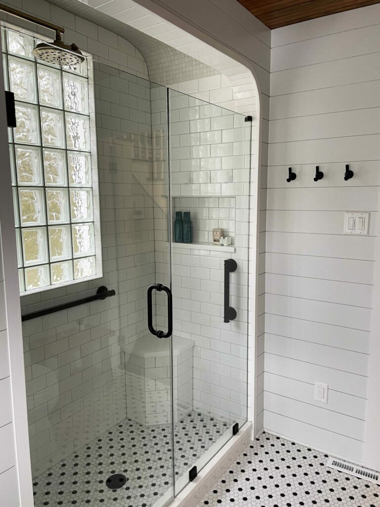 vintage bathroom with barrel ceiling over the shower, shiplap walls and black and white mosaic floor tiles