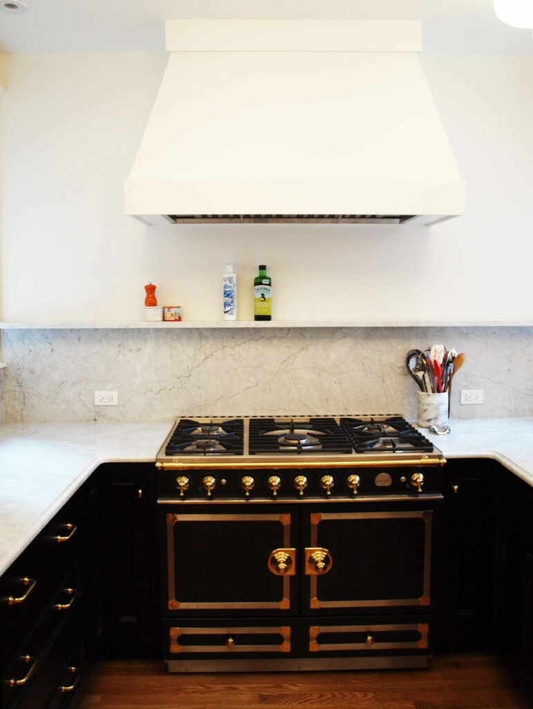 black La Cornue range under a white simple drywall hood in a French inspired kitchen