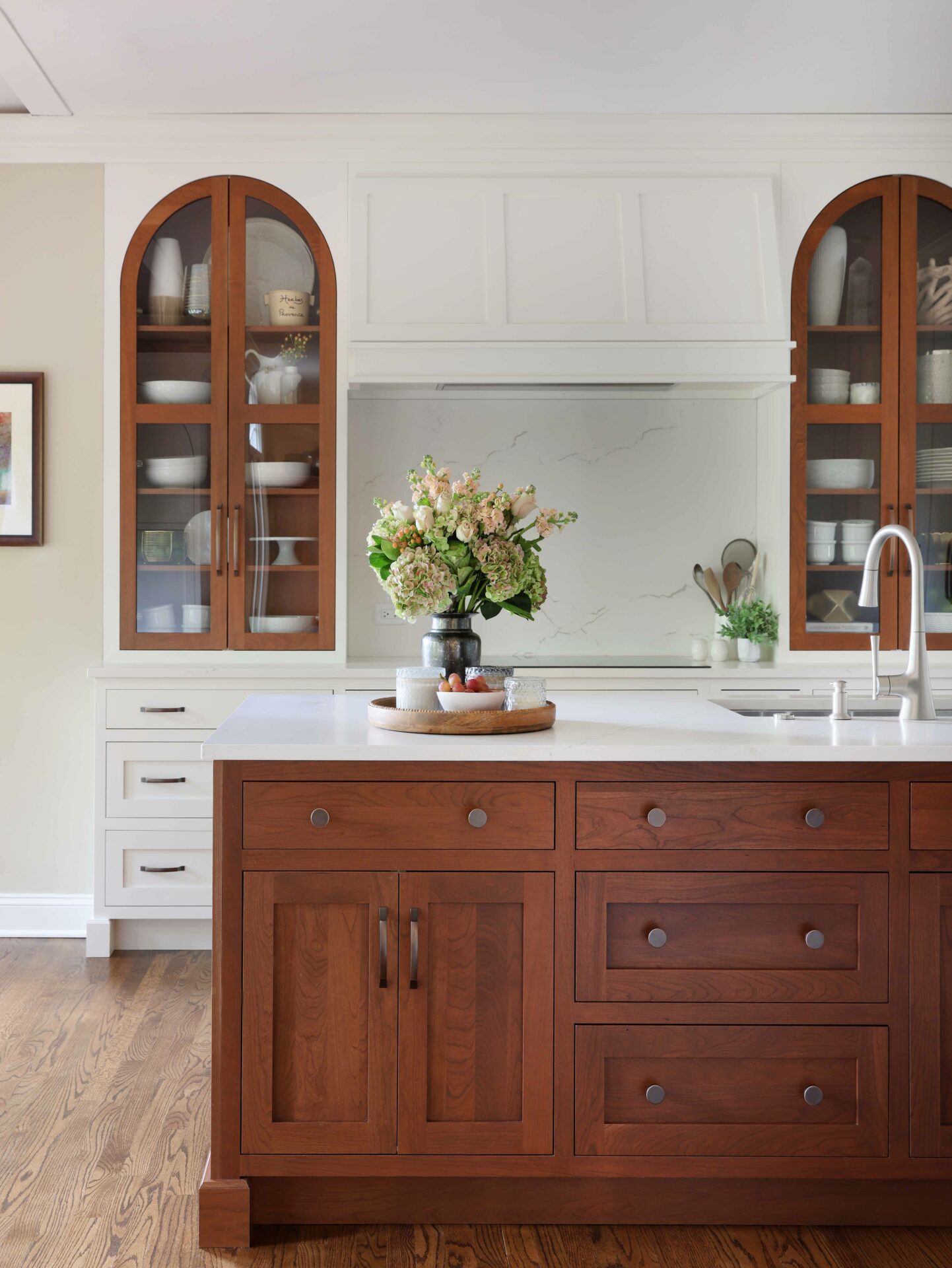 Winter white kitchen with slab backsplash and cherry stained island and accent cabinets