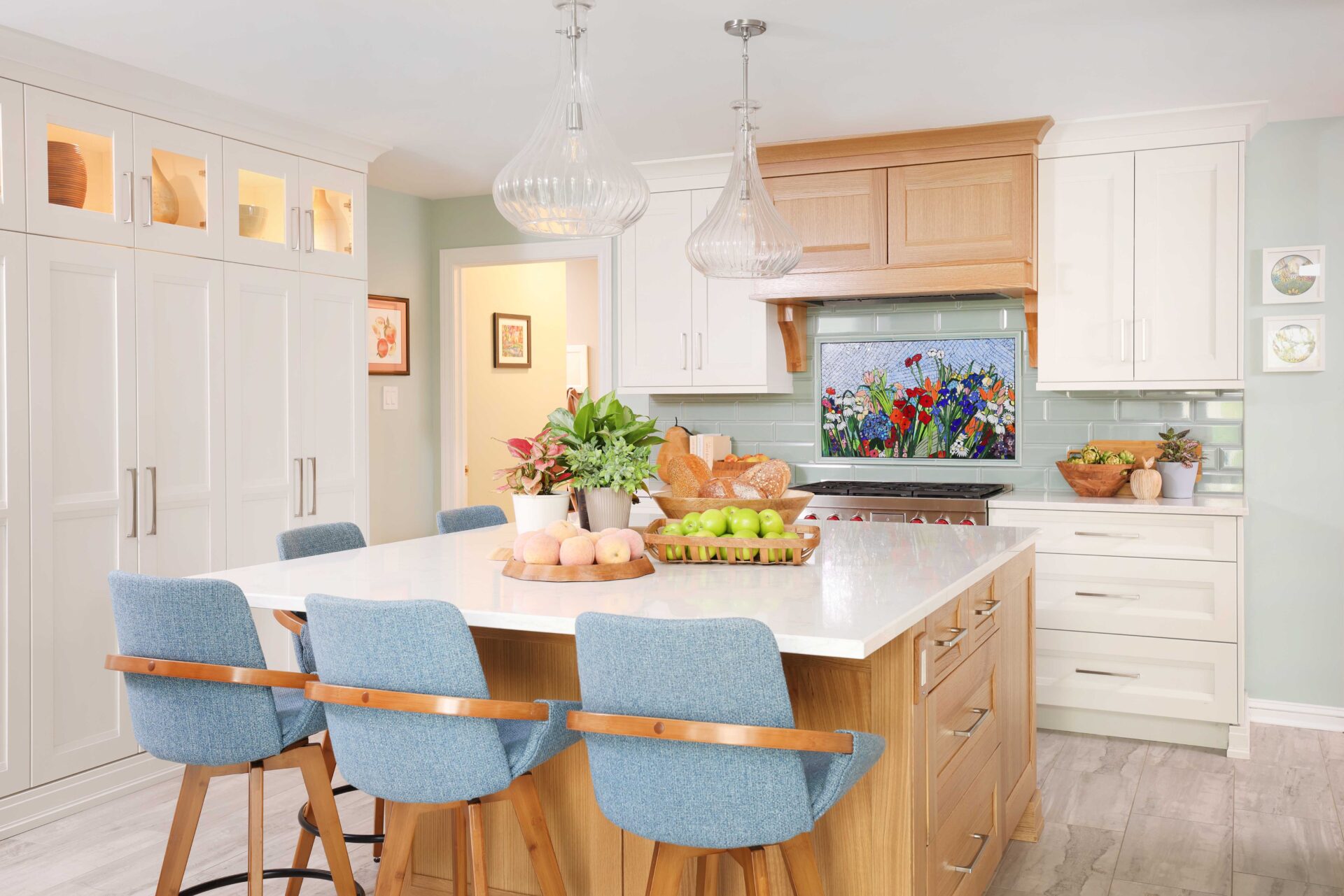 White kitchen cabinets and countertops, rift cut white oak range hood and kitchen island, color mosaic backsplash light blue fabric high-backed bar stools