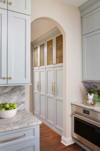 Butler pantry cabinet in a soft blue color with gold mesh inserts
