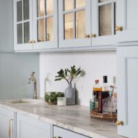 Wet bar with light blue cabinetry and antique mirror cabinet fronts