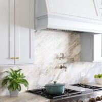 Light blue traditional style kitchen with range hood, slab backsplash and pot filler