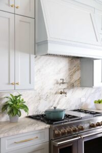 Light blue traditional style kitchen with range hood, slab backsplash and pot filler