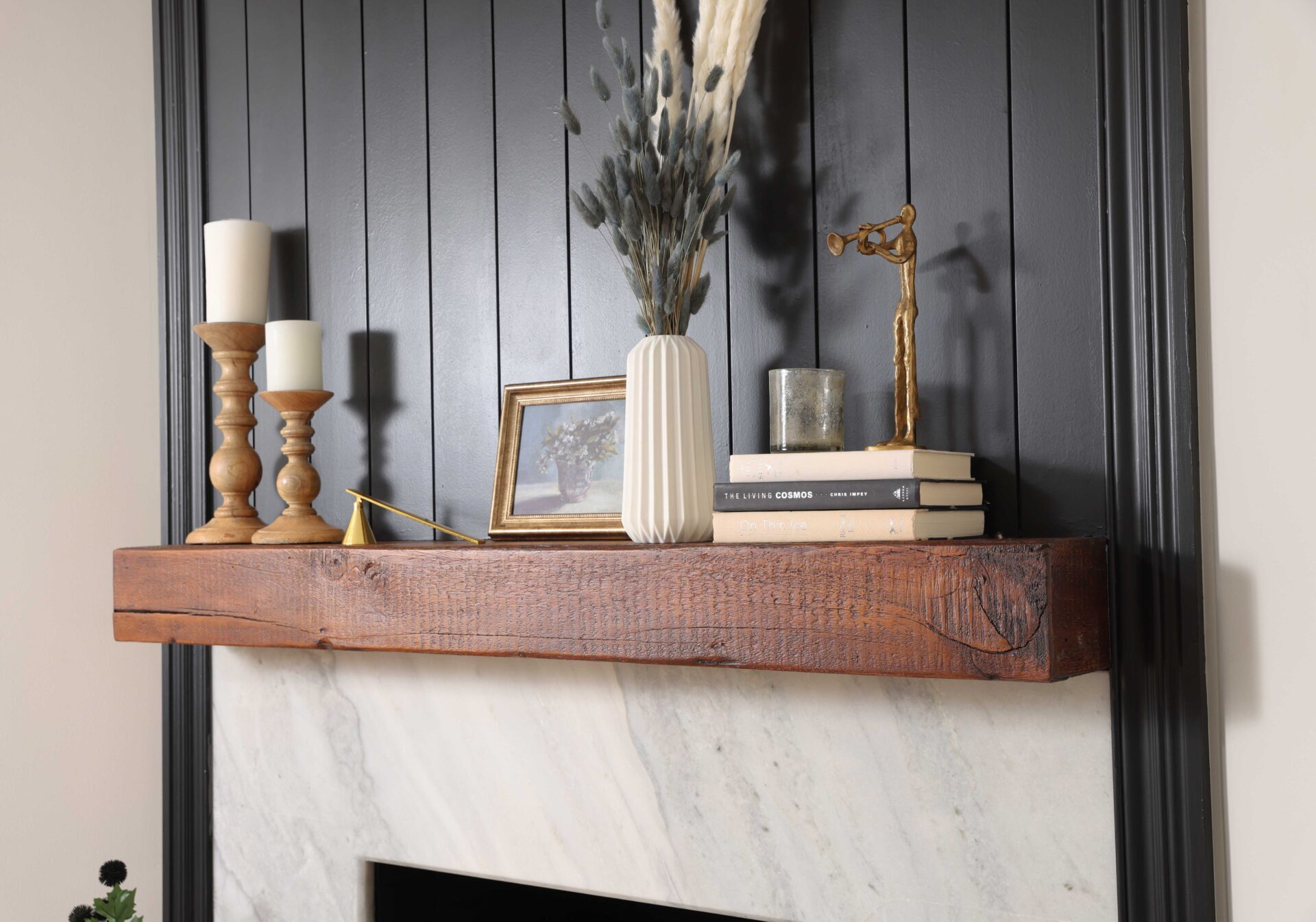 White stone fireplace face, wood mantle, dark painted wainscot paneling beadboard