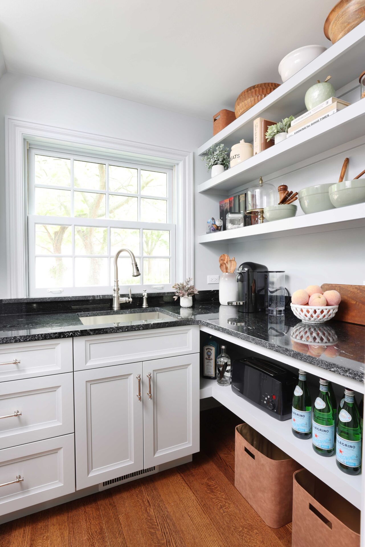 White kitchen pantry with sink, polished nickel faucet and black countertops