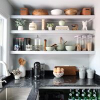 White kitchen pantry with sink, polished nickel faucet and black countertops, window above sink