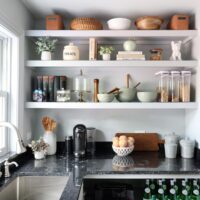 White kitchen pantry with sink, polished nickel faucet and black countertops, window above sink