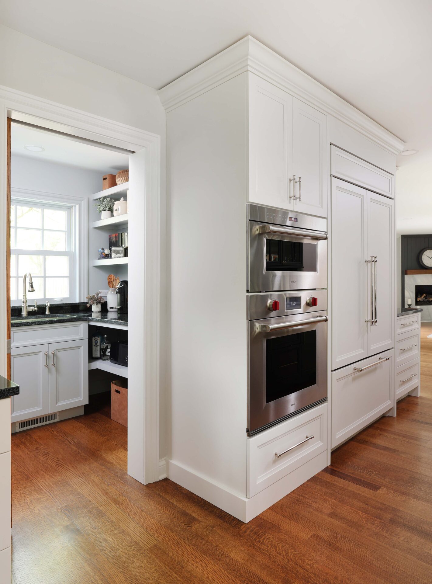 Double stainless steel ovens, white paneled refrigerator, walk-in pantry with sink