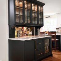 Home bar with black cabinetry, beverage fridge, glass-paneled upper cabinets, hidden appliance garage for liquor