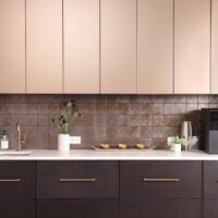 The modern beverage center features rift cut white oak cabinetry, ceramic tile backsplash, quartz countertops, wine fridge, integrated refrigerator drawers, brushed brass elements, and fireclay basin.