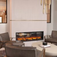Modern minimalist fireplace features vertical ceramic tile surround and brushed brass decorative band. Striking brass light fixture hangs overhead, complimenting the verticality of the design. The electric fireplace itself delivers warm ambience without the need for venting.
