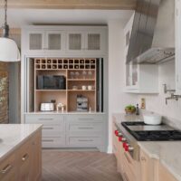Modern farmhouse kitchen island features a baking center with a pull-out bread drawer, warming drawer and mixer lift.