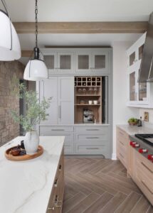 Modern farmhouse kitchen includes custom hutch with decorative feet and bi-fold pocket doors. Hutch can serve as storage or an improvised beverage center.