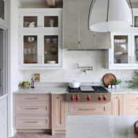 Modern farmhouse kitchen includes custom stainless steel hood with polished nickel strapping.