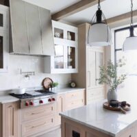 Modern farmhouse kitchen includes rift cut white oak cabinets in natural and white painted finishes. The refrigerator cabinet features polished nickel mesh panels, adding subtle texture and shine.
