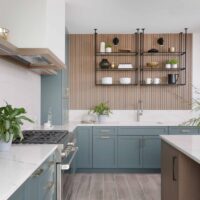 The color forward contemporary kitchen features sleek slab-front doors at the island — a modern take on inset cabinets, which typically leans more traditional — creating visual interest without overwhelming the space. Quartz countertops further balance the design with a calm, neutral surface.