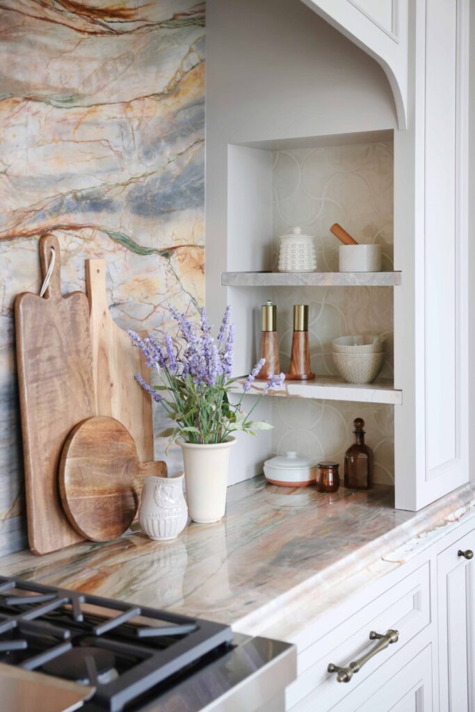 The elevated new traditional kitchen features 48-inch range with Tudor style arched hood. Full height quartzite backsplash with rose and caramel veining. Range area has recessed spice niches.
