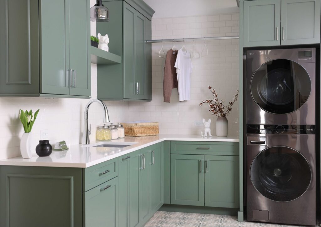 The colorfully classic laundry room features rich green cabinets, floating shelves, subway tile, quartz countertop, gray sink, polished chrome hardware, printed floor tile. Organizational solutions include pull out drying rack, hanging pole for steaming or storing garments, and lots of counterspace for folding.