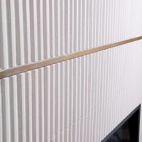 White fireplace surround with vertical tile and brass metal banding