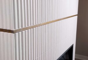 White fireplace surround with vertical tile and brass metal banding