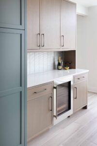 Bar with rift cut white oak cabinetry, white quartz countertops and glass tile backsplash