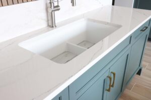 Smart divide white composite sink with white quartz countertops, rainforest blue-green cabinets