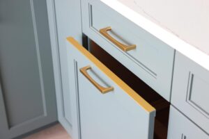 Honey bronze drip edge at trash cabinet, rainforest blue green cabinets
