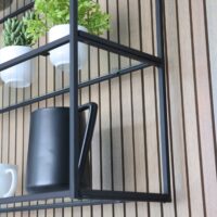 Rift cut white oak vertical slat paneling at sink wall, matte black hanging shelves