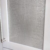 Rift cut white oak paneled refrigerator with polished nickel mesh panels and handle