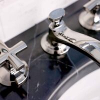 Black marble sink vanity top with polished nickel faucet and cross handles from Kallista