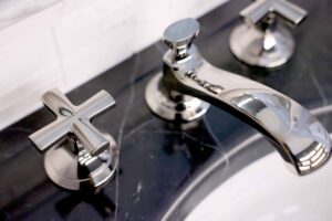 Black marble sink vanity top with polished nickel faucet and cross handles from Kallista