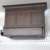 Cherry hood with ivory white beveled picket tile backsplash and sconces
