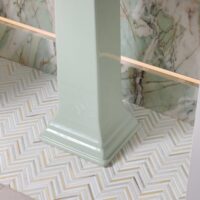Marble floor tile in herringbone pattern in green powder room, porcelain feature wall with integrated LED lighting