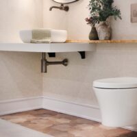 Floating toilet and floating vanity in accessible design powder room, olive wood ledge, porcelain tile flooring, vessel sink, wall-mounted faucet