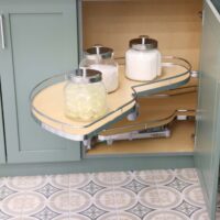 Lazy Susan pull out shelf in laundry room with green cabinets, patterned tile floor, polished chrome hardware