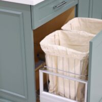 Double hamper drawer in green cabinet laundry room with decorative cabinet molding