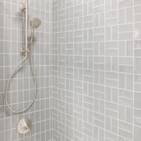 Brushed nickel shower head, soft gray tile, two different tile arrangements