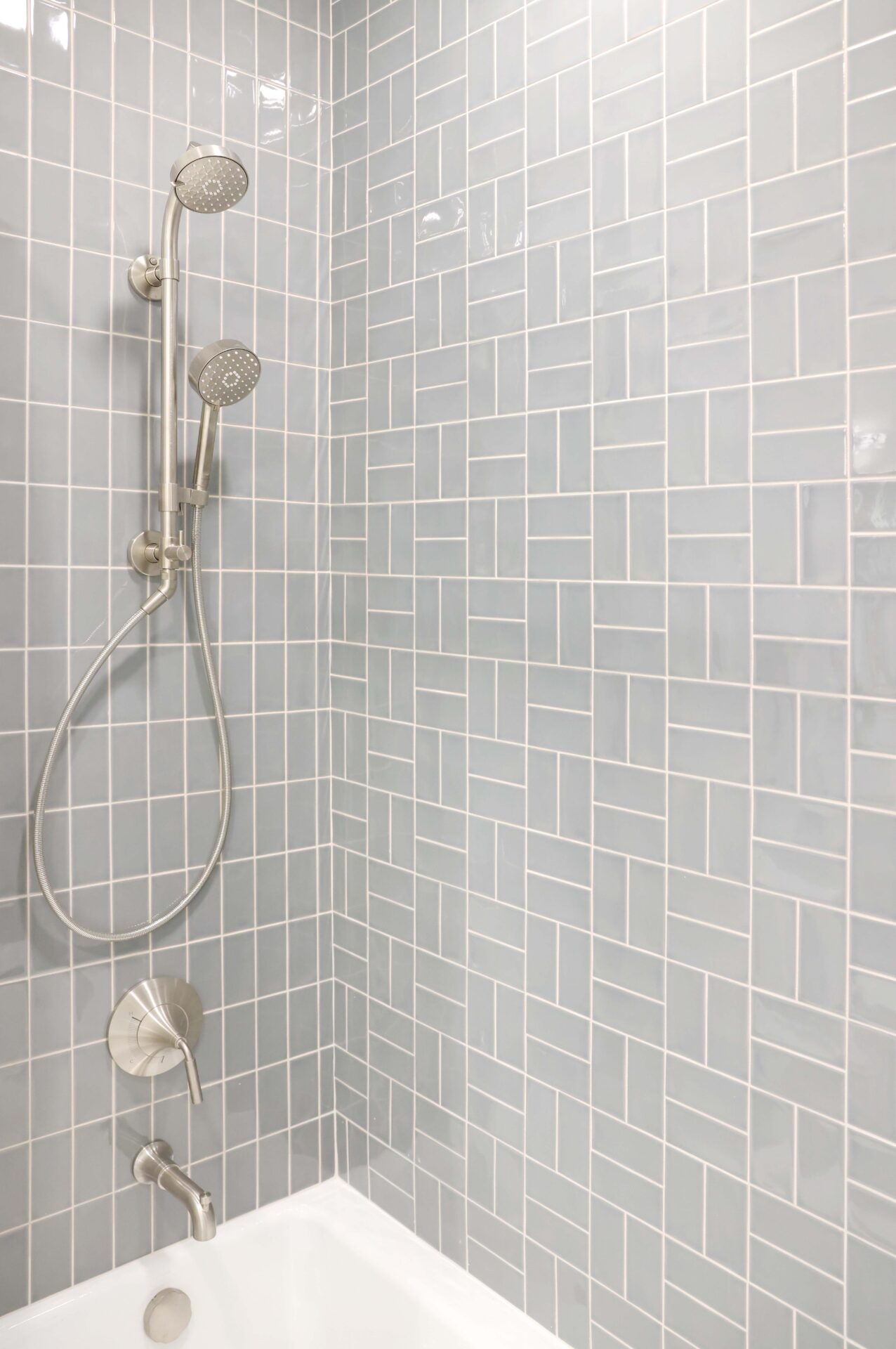 Brushed nickel shower head, soft gray tile, two different tile arrangements