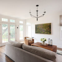 Classic Elmhurst First Floor Renovation includes a spacious family room with natural light flowing through French doors. The doors are separated by decorative pilasters and sconce lighting.