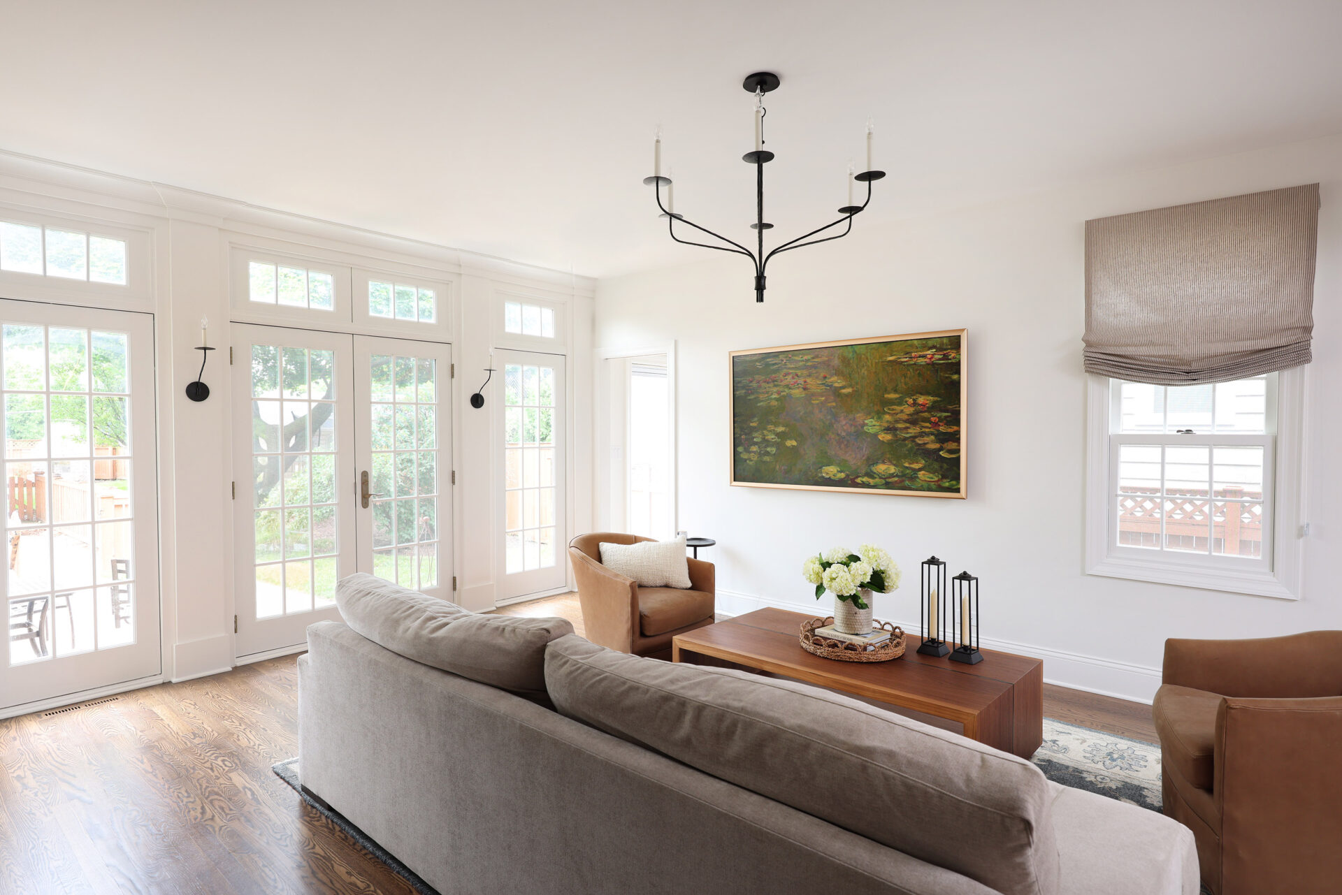 Classic Elmhurst First Floor Renovation includes a spacious family room with natural light flowing through French doors. The doors are separated by decorative pilasters and sconce lighting.
