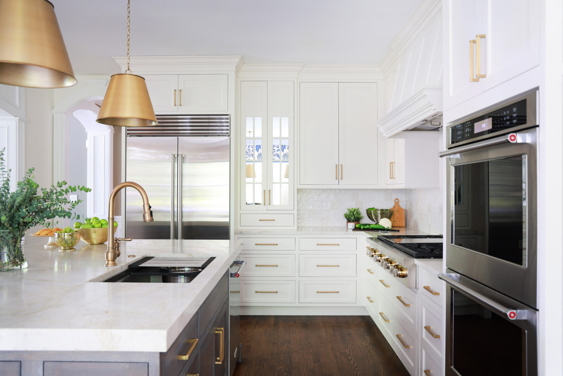 Updated traditional kitchen: The island includes a workstation sink with a ledge for accessories, paired with a brushed bronze faucet, all positioned closer to the cooktop for easier access.