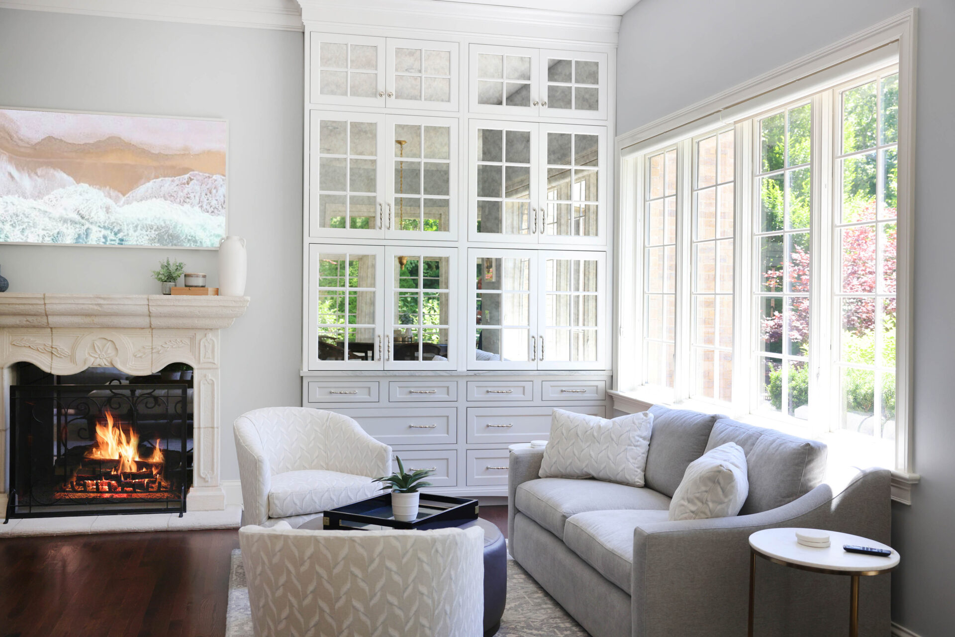 Fireplace with TV above, windows looking into backyard, kitchen couch, white and gray