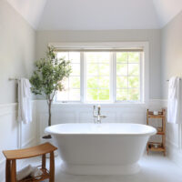 Freestanding white tub under windows, volcanic limestone, polished nickel
