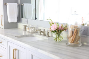 Blue gray countertop with polished nickel faucet and gold cabinet hardware