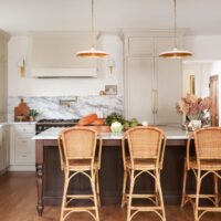 Warm white kitchen with modern vintage details, marble countertops and backsplash with shelf, red oak island, island seating, farmhouse sink, paneled fridge, sconces, brass hardware