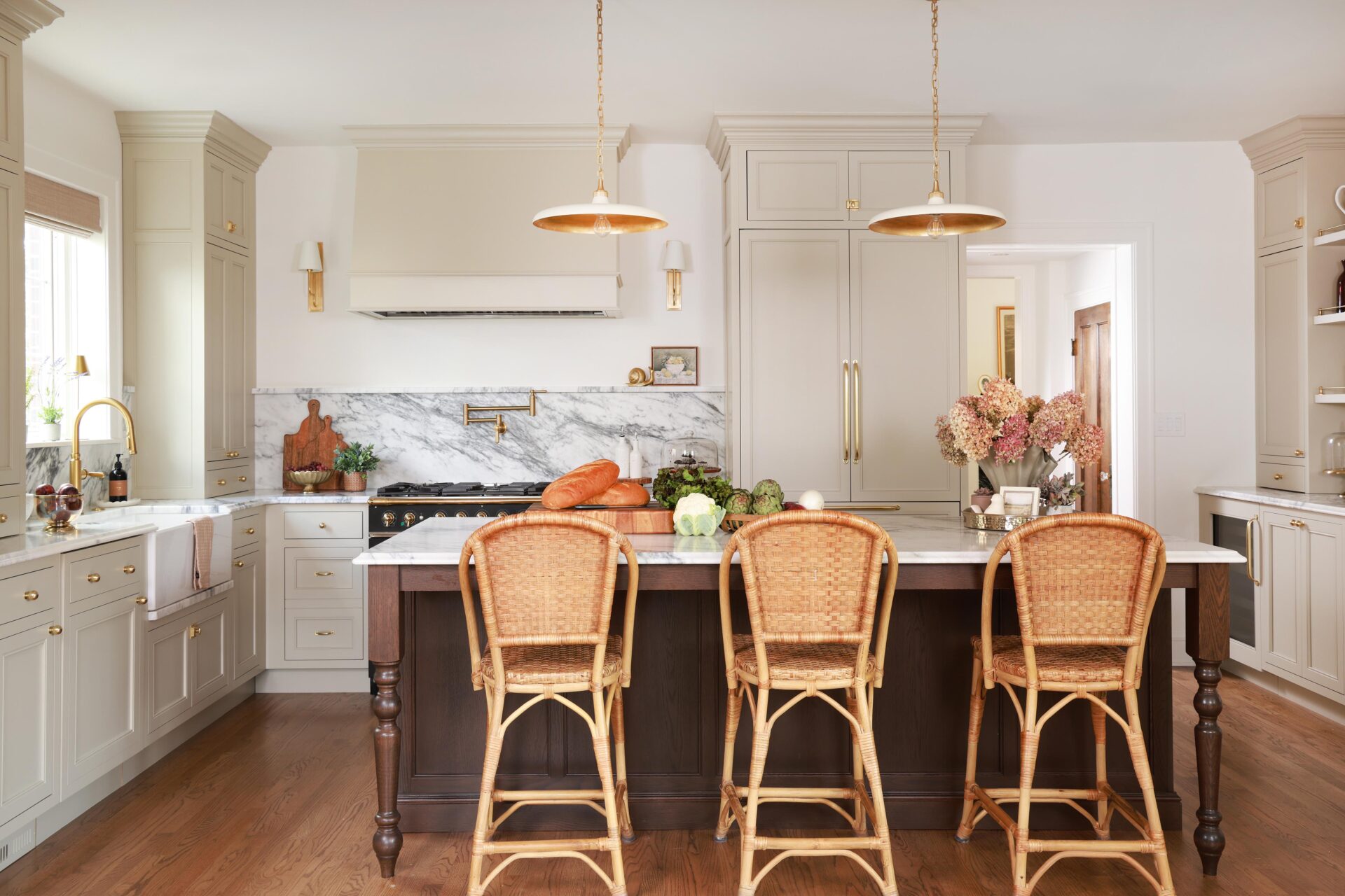Warm white kitchen with modern vintage details, marble countertops and backsplash with shelf, red oak island, island seating, farmhouse sink, paneled fridge, sconces, brass hardware