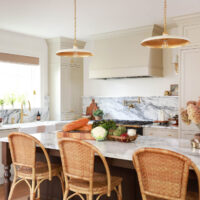 Warm white kitchen with modern vintage details, marble countertops and backsplash with shelf, red oak island, island seating wicker bar stools, farmhouse sink, paneled fridge, sconces, brass hardware, to the ceiling cabinets, inset cabinetry