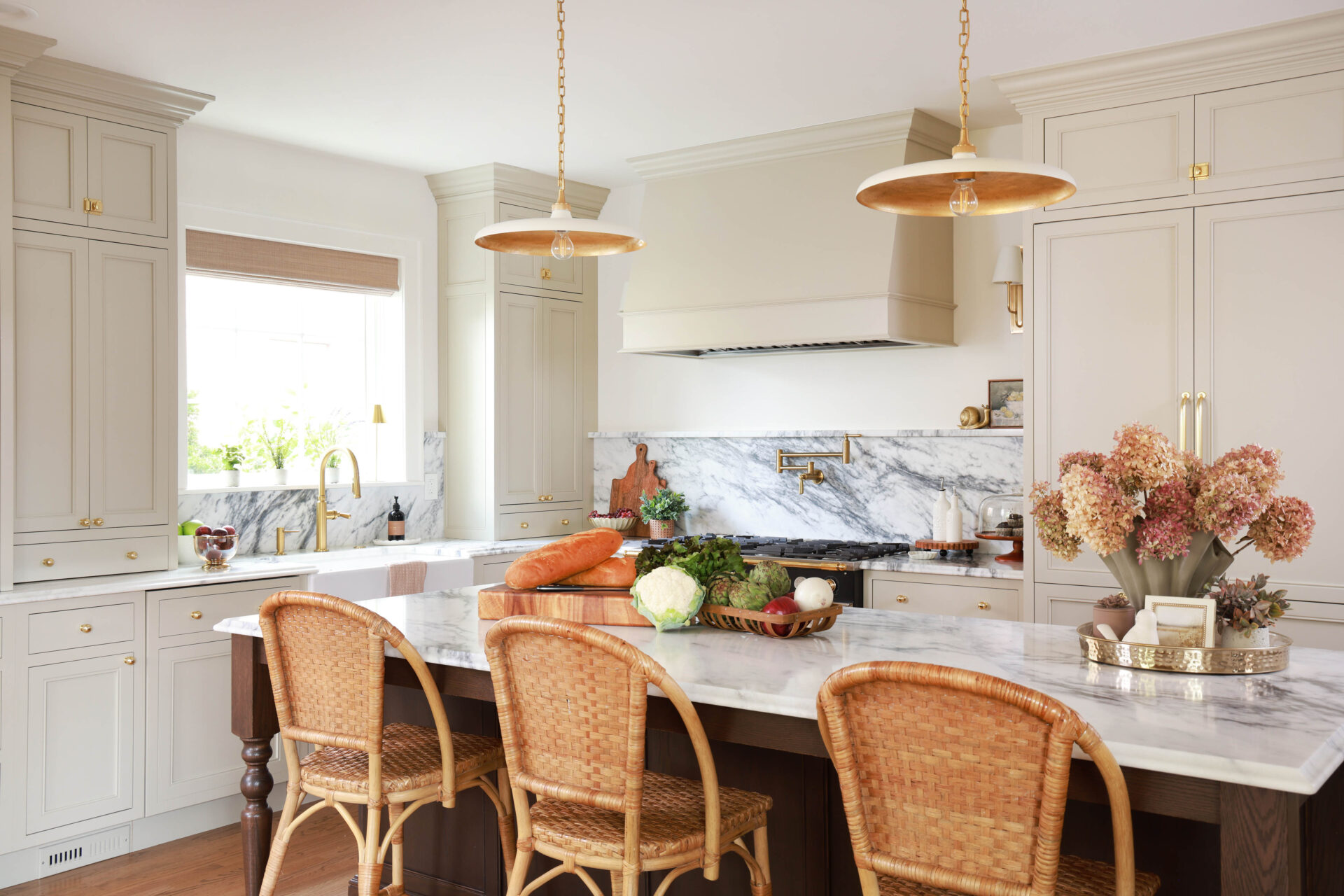Warm white kitchen with modern vintage details, marble countertops and backsplash with shelf, red oak island, island seating wicker bar stools, farmhouse sink, paneled fridge, sconces, brass hardware, to the ceiling cabinets, inset cabinetry