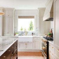 Warm white kitchen with modern vintage details, marble countertops, red oak island, farmhouse sink, with drip ledge, paneled fridge, brass hardware and knobs, to the ceiling cabinets, inset cabinetry, window above sink, set on backsplash in marble